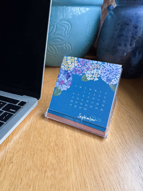 Small calendar on a desk next to a laptop